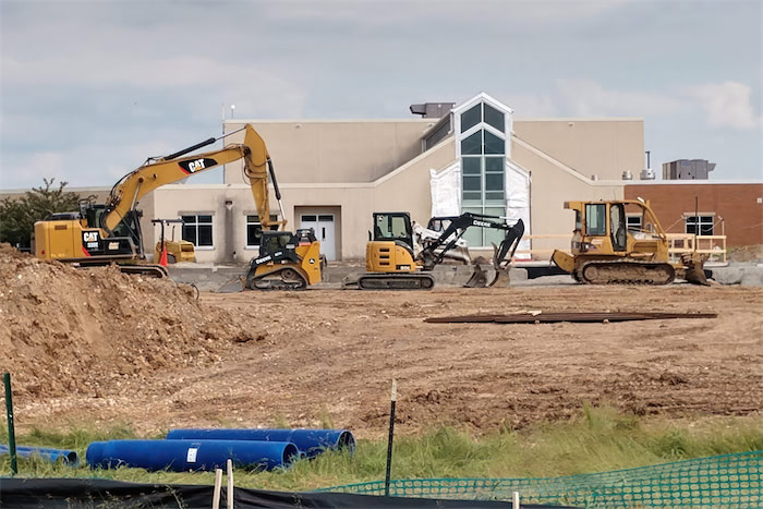 Four construction vehicles working infront of a church